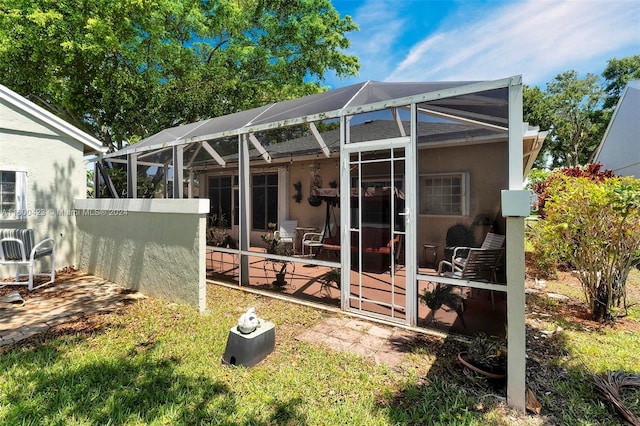 rear view of house with glass enclosure and a patio area