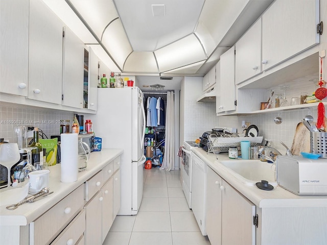 kitchen featuring sink, light tile patterned floors, tasteful backsplash, white appliances, and white cabinets