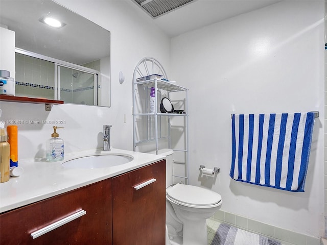 bathroom featuring a shower with door, vanity, and toilet