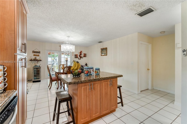 kitchen featuring a notable chandelier, a breakfast bar, a textured ceiling, and light tile floors