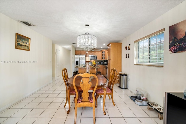 tiled dining room featuring an inviting chandelier and a textured ceiling