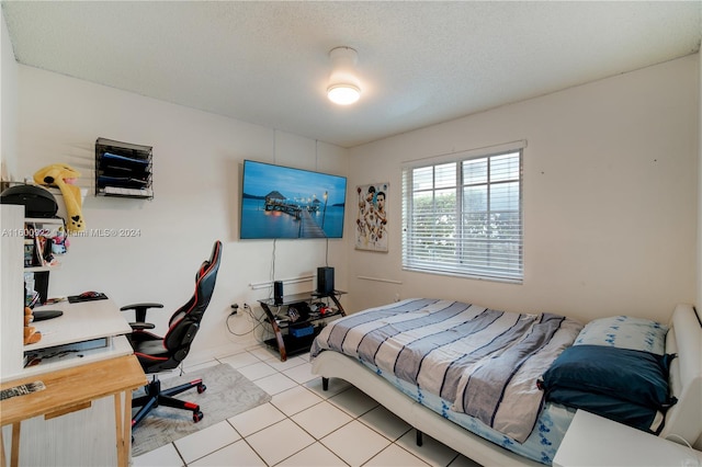 bedroom with a textured ceiling and light tile floors