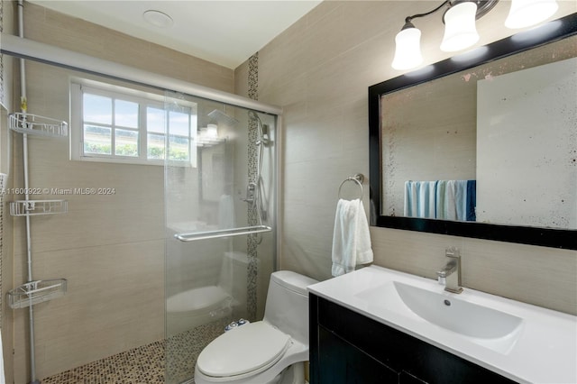 bathroom with tile walls, an enclosed shower, vanity, and toilet