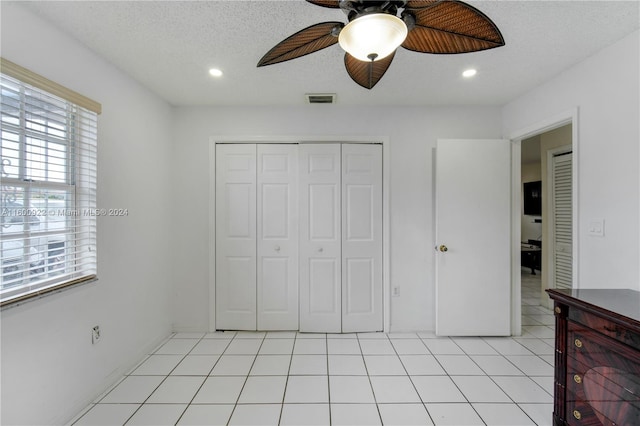 unfurnished bedroom with a textured ceiling, a closet, ceiling fan, and light tile floors