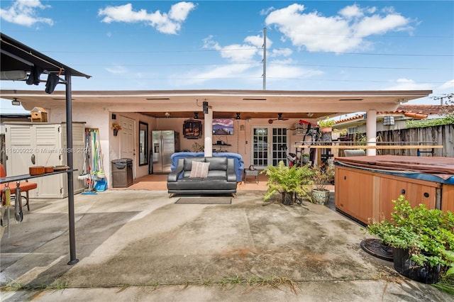 view of terrace with a hot tub, french doors, and ceiling fan