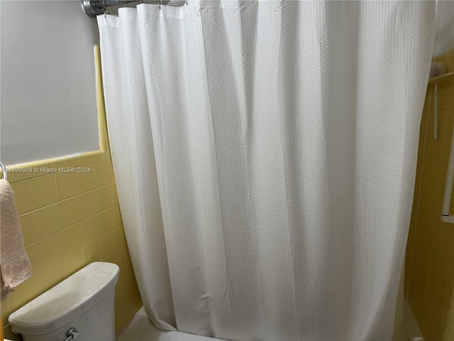 bathroom featuring tile walls and toilet