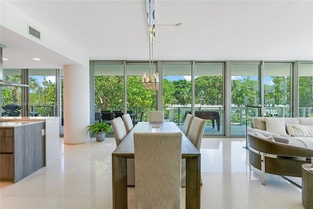 tiled dining area with a wealth of natural light, a notable chandelier, and floor to ceiling windows