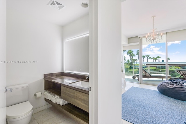 bathroom with an inviting chandelier, vanity, toilet, and tile floors