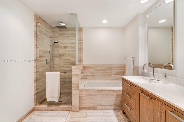 bathroom with tile floors, shower with separate bathtub, and vanity with extensive cabinet space