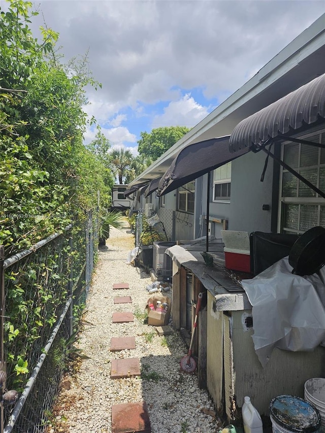 view of side of property featuring central AC unit, fence, and stucco siding