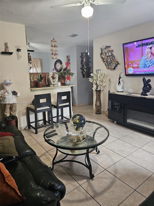 living area featuring light tile patterned floors, a ceiling fan, and visible vents