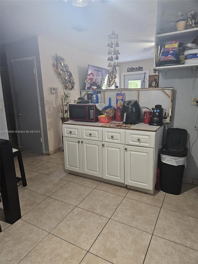 kitchen featuring light tile patterned flooring, a peninsula, white cabinetry, and light countertops