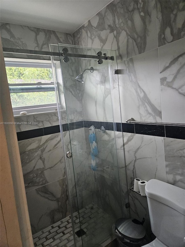 full bath featuring toilet and a marble finish shower