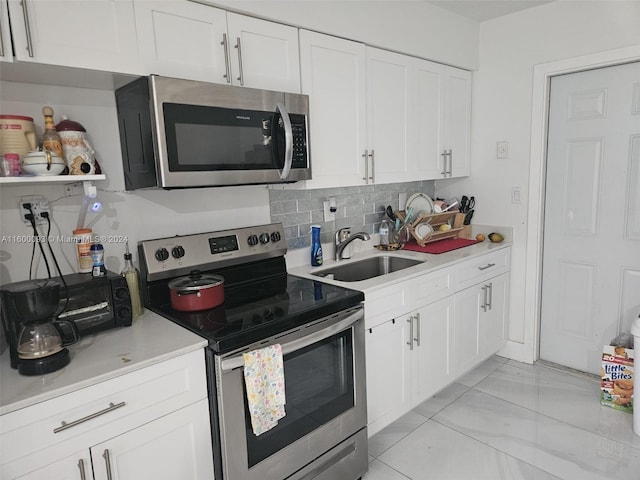kitchen with a sink, stainless steel appliances, light countertops, white cabinetry, and backsplash