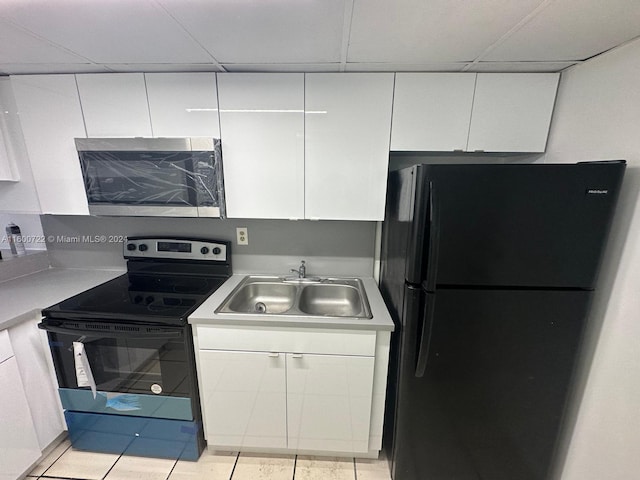 kitchen with light tile patterned flooring, sink, white cabinets, and black appliances