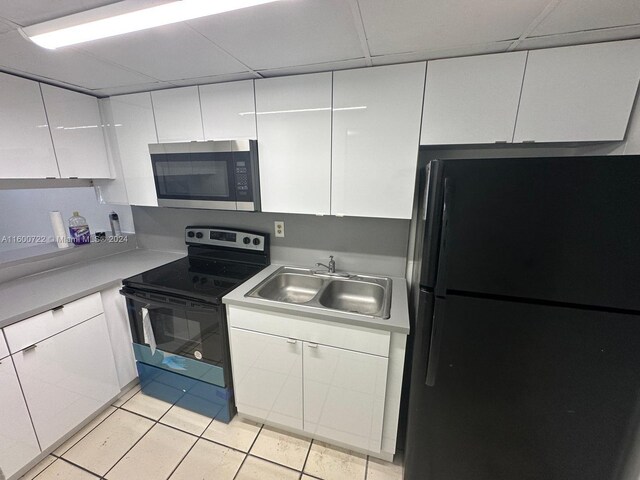 kitchen with light tile patterned floors, electric range oven, sink, and black refrigerator