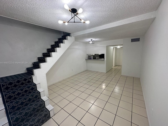 basement featuring a notable chandelier, a textured ceiling, and light tile patterned floors