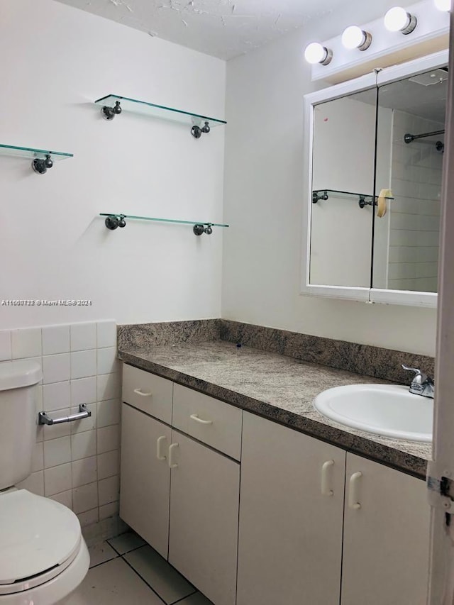 bathroom with tile patterned flooring, tile walls, toilet, and vanity