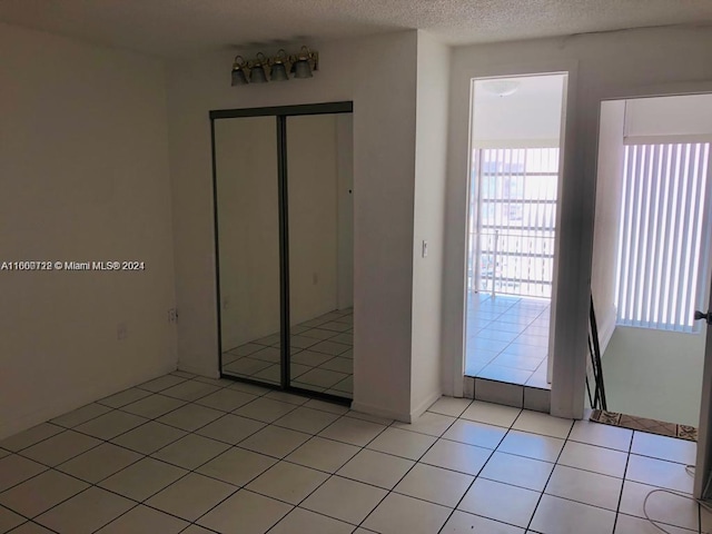 interior space with a textured ceiling, a closet, and light tile patterned floors