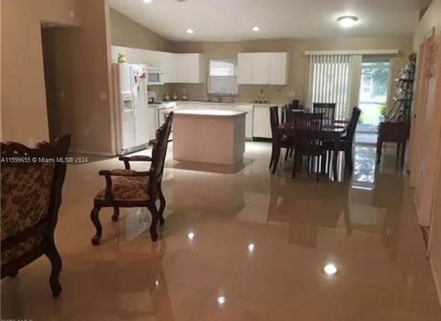 kitchen with a kitchen island, white cabinets, white appliances, and light tile floors