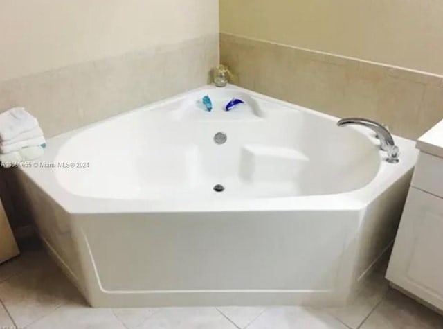 bathroom with tile floors, vanity, and a tub