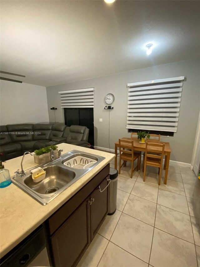 kitchen with dark brown cabinetry, sink, and light tile patterned floors