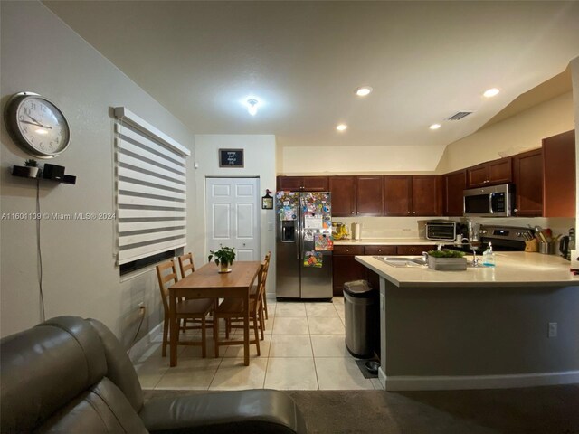 kitchen featuring kitchen peninsula, appliances with stainless steel finishes, light tile patterned floors, and sink