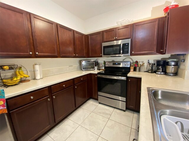 kitchen with sink, appliances with stainless steel finishes, and light tile patterned floors