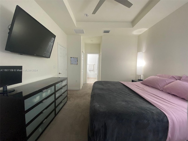 carpeted bedroom featuring ensuite bath, ceiling fan, and a tray ceiling