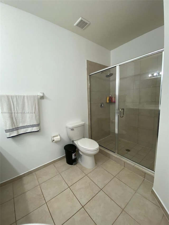 bathroom with toilet, tile patterned floors, and a shower with door