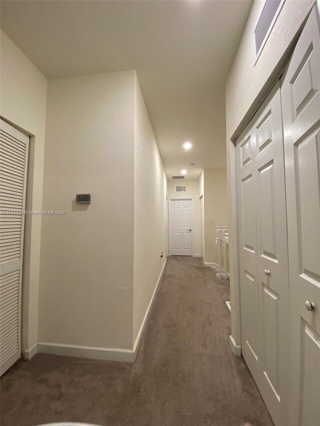 hall featuring dark colored carpet