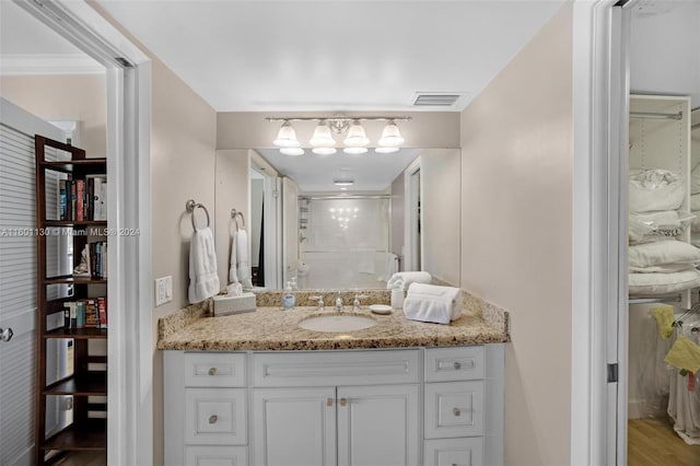 bathroom with hardwood / wood-style flooring, vanity, a shower with door, and crown molding