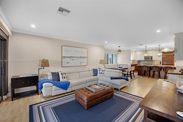 living room with crown molding and light hardwood / wood-style flooring