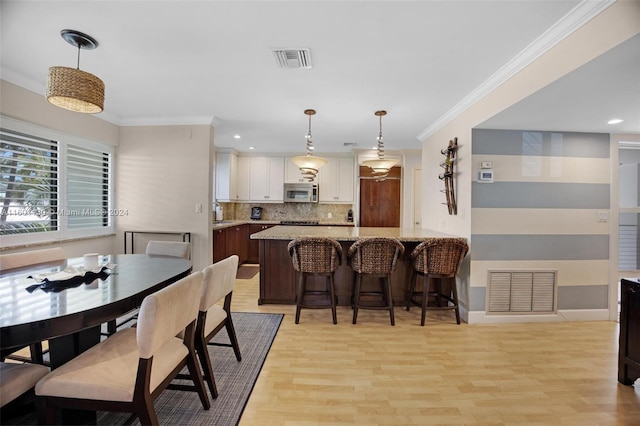 dining space featuring light hardwood / wood-style flooring and ornamental molding