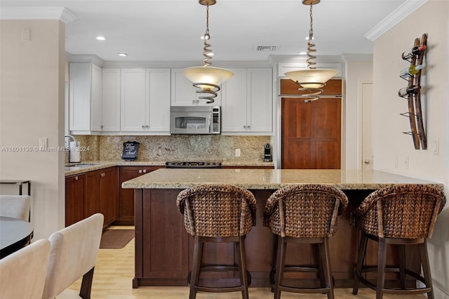 kitchen featuring white cabinets, pendant lighting, and light stone counters