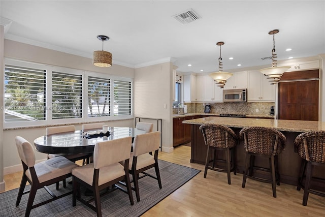 dining room featuring light hardwood / wood-style floors, ornamental molding, and sink