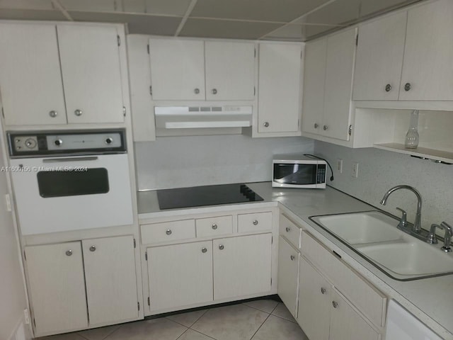 kitchen featuring white appliances, white cabinets, sink, light tile patterned floors, and tasteful backsplash