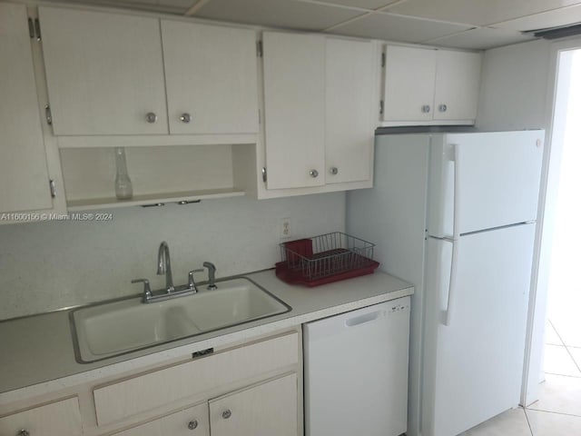 kitchen with white cabinets, white appliances, sink, and light tile patterned flooring