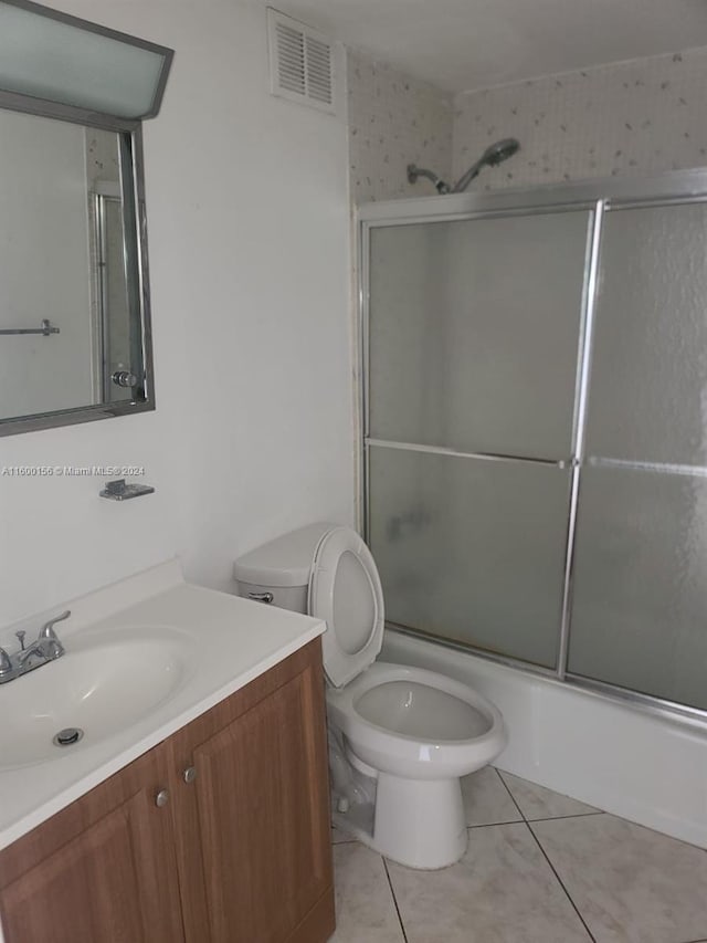 full bathroom with toilet, vanity, tile patterned floors, and bath / shower combo with glass door