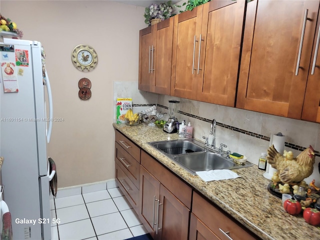 kitchen with white fridge, light stone counters, tasteful backsplash, and sink