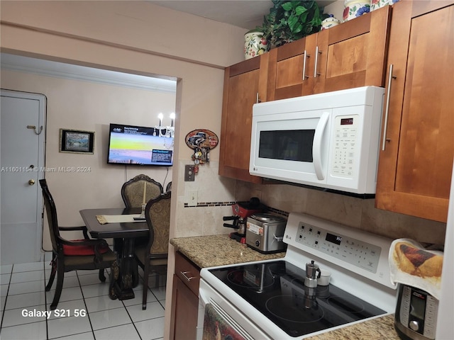 kitchen with light tile patterned floors, backsplash, electric range oven, and light stone counters