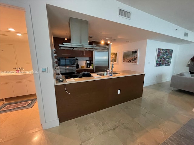 kitchen with wall chimney range hood, sink, light tile patterned flooring, and stainless steel appliances