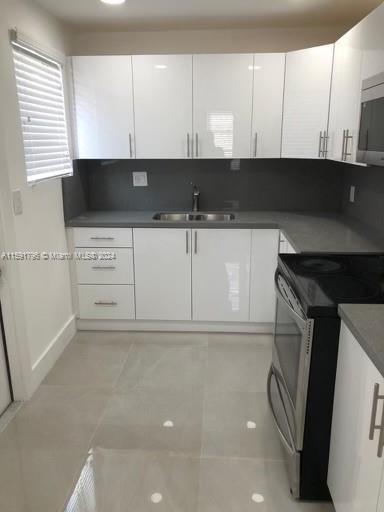 kitchen featuring white cabinets, stainless steel appliances, light tile patterned flooring, and sink