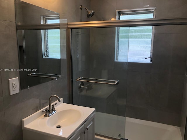 bathroom with vanity, enclosed tub / shower combo, and backsplash