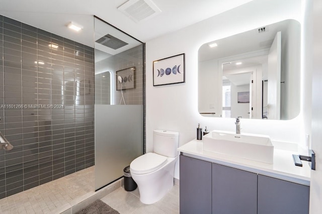 bathroom with a tile shower, vanity, tile patterned flooring, and toilet