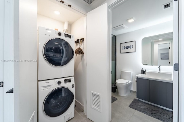 laundry room featuring stacked washing maching and dryer, sink, and light tile patterned floors