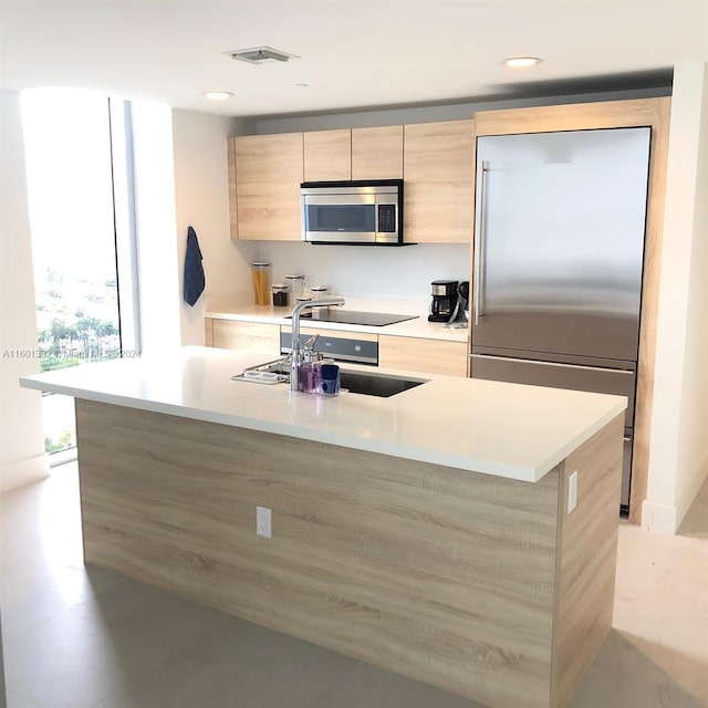 kitchen featuring sink, light brown cabinetry, an island with sink, and appliances with stainless steel finishes