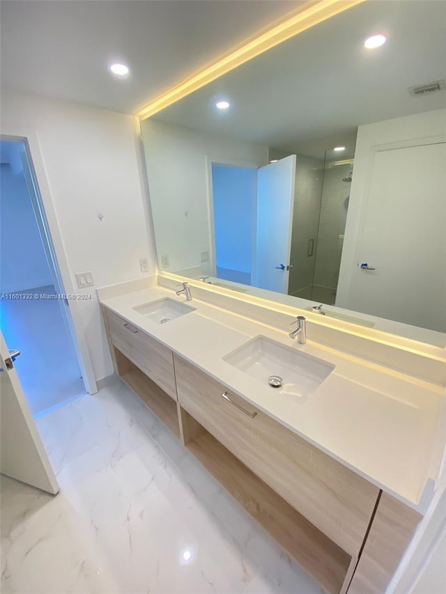 bathroom featuring a shower with door and vanity