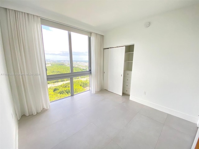 unfurnished bedroom featuring a wall of windows and a closet