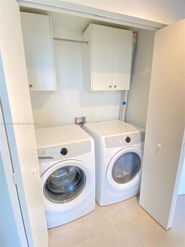 laundry area with light tile patterned floors, cabinets, and independent washer and dryer